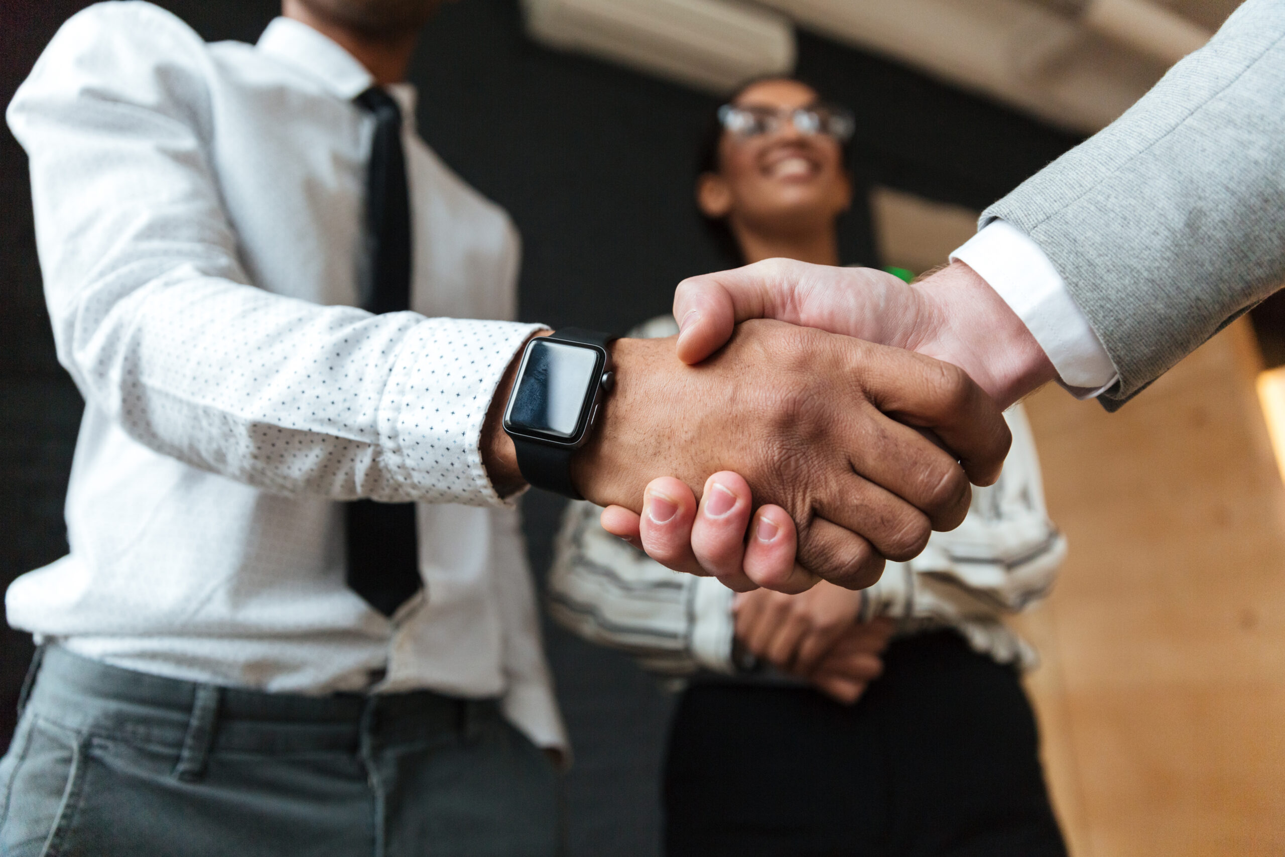 Cropped photo of handshake of young colleagues indoors coworking. Focus on hands.
