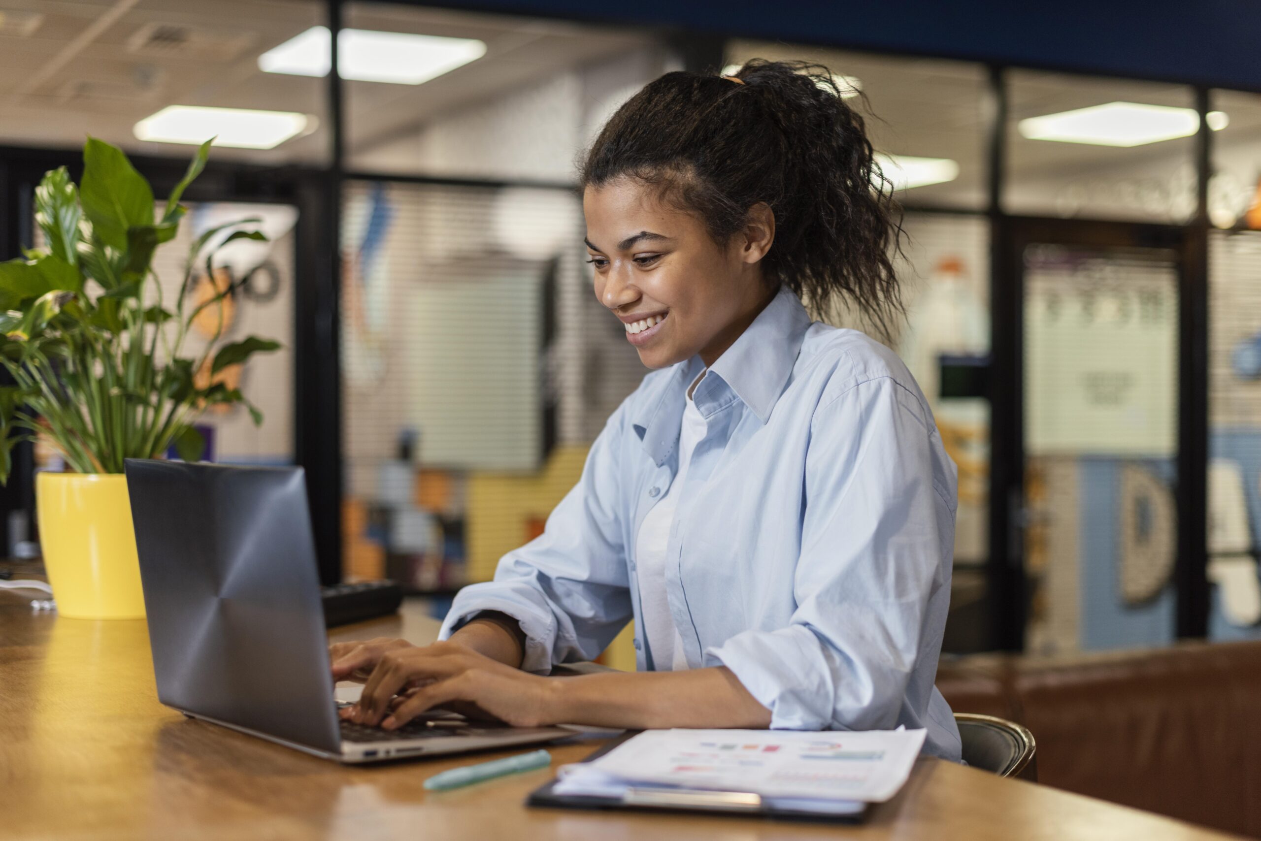 Side view smiley woman working with laptop office